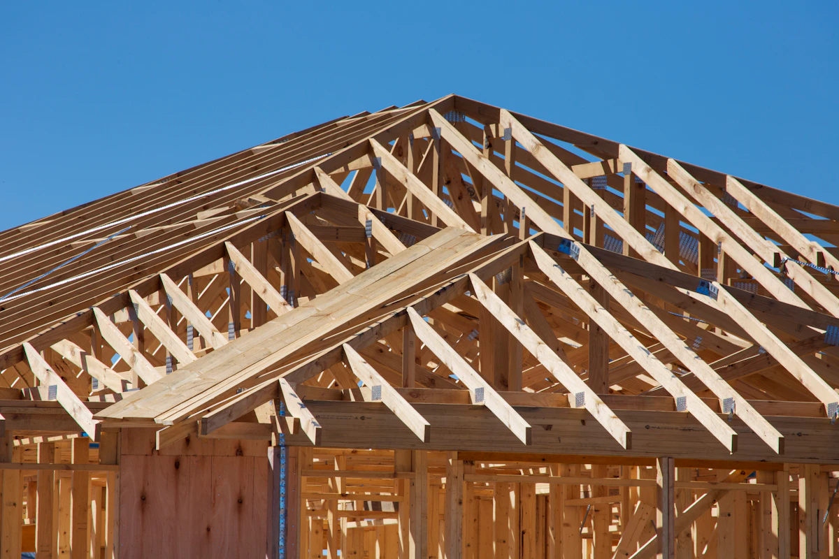 Wooden framing of a new house under construction against a blue sky