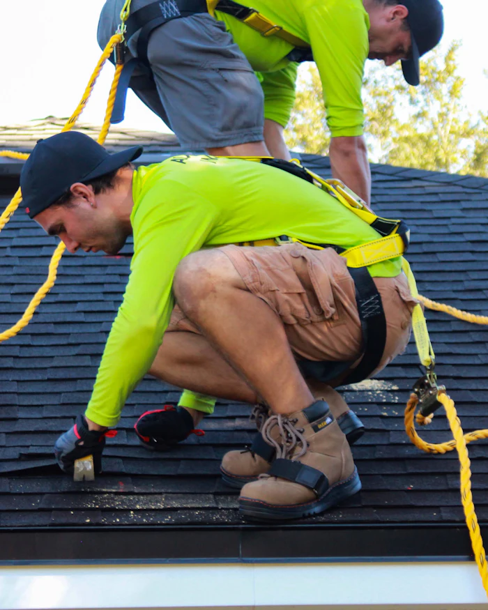 Two roofers installing shingles on a residential roof